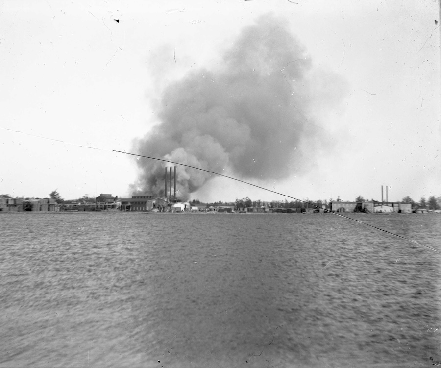 Black and White photograph of Oval Dish Factory fire in the distance