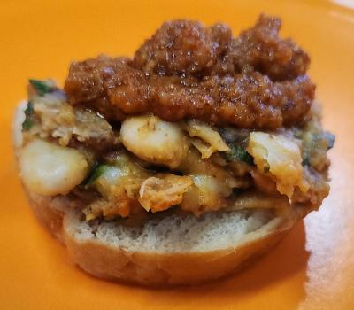 crostini topped with beans and greens and romesco sauce on a yellow plate