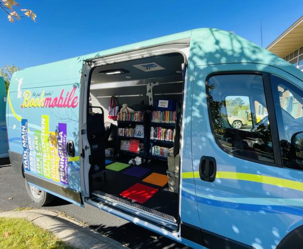 Bookmobile with door open showing books and book carts